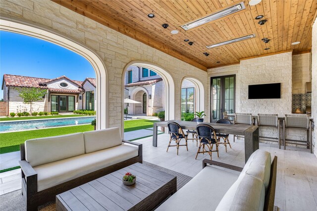 view of patio with exterior bar and an outdoor living space with a fireplace