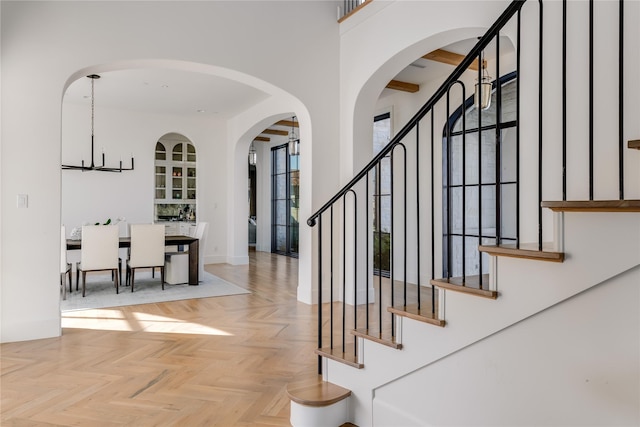 stairs with an inviting chandelier and parquet flooring