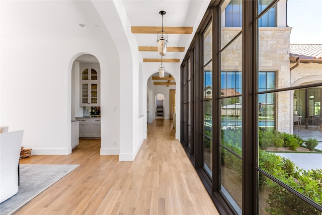 hallway with light hardwood / wood-style flooring and beamed ceiling