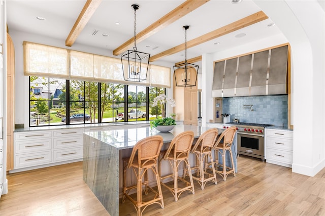 kitchen with white cabinetry, light stone countertops, a center island, and luxury stove