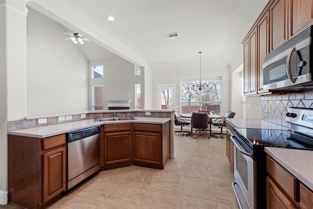 kitchen with lofted ceiling, stainless steel appliances, tasteful backsplash, sink, and hanging light fixtures