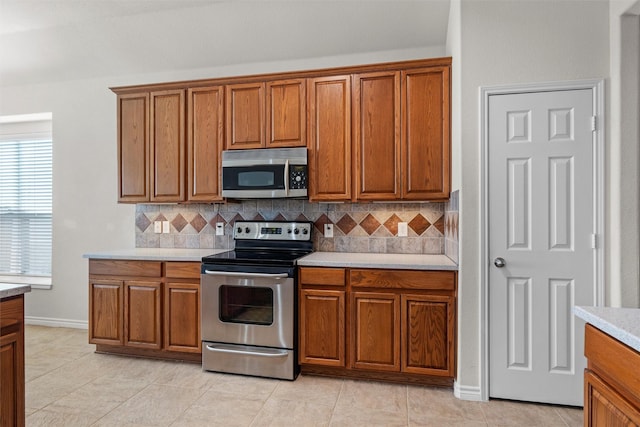 kitchen featuring stainless steel appliances, decorative backsplash, and light tile patterned flooring