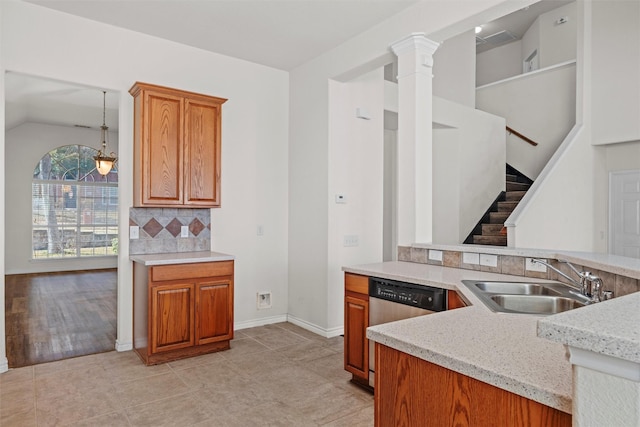 kitchen with kitchen peninsula, ornate columns, sink, decorative light fixtures, and tasteful backsplash