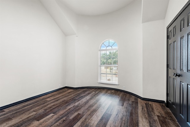 unfurnished room featuring a high ceiling and dark wood-type flooring