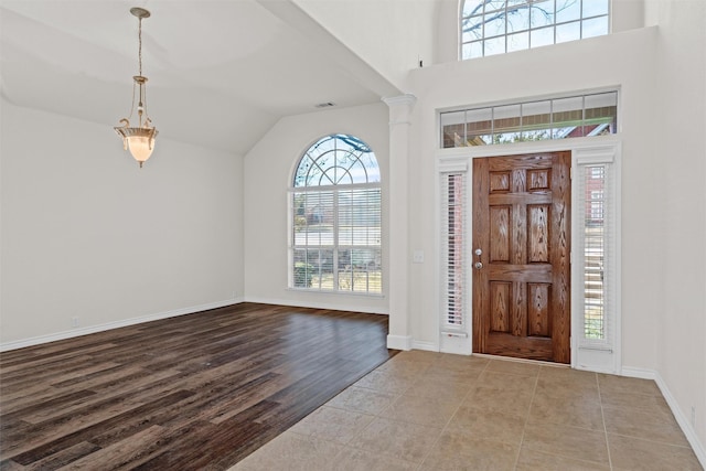 foyer entrance featuring decorative columns, lofted ceiling, and light hardwood / wood-style floors