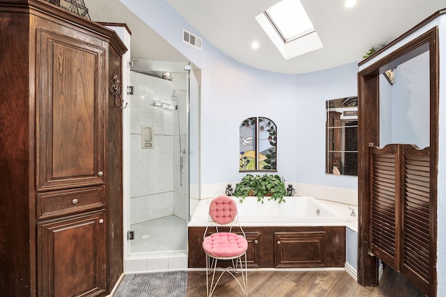 full bathroom featuring a skylight, a stall shower, visible vents, wood finished floors, and a garden tub