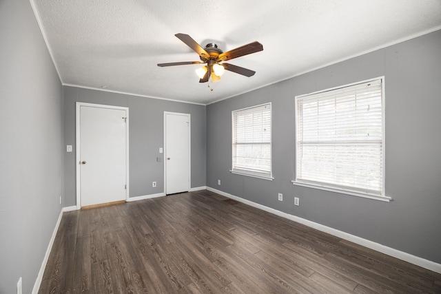 empty room featuring baseboards, a ceiling fan, dark wood-style flooring, crown molding, and a textured ceiling