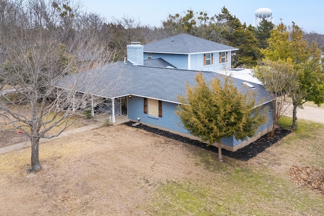 exterior space with a shingled roof, driveway, and a chimney