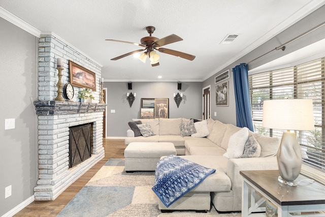 living room featuring hardwood / wood-style flooring, ceiling fan, ornamental molding, and a fireplace