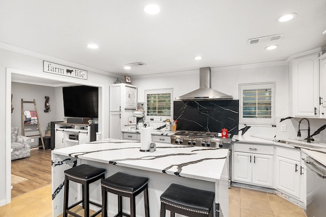 kitchen featuring stainless steel dishwasher, wall chimney exhaust hood, sink, and white cabinets