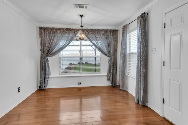 unfurnished dining area with a notable chandelier, hardwood / wood-style flooring, and ornamental molding