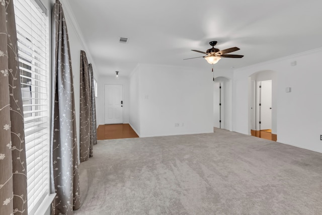 carpeted spare room with ceiling fan, a wealth of natural light, and crown molding