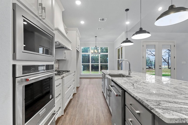 kitchen featuring a kitchen island with sink, white cabinetry, pendant lighting, and stainless steel appliances