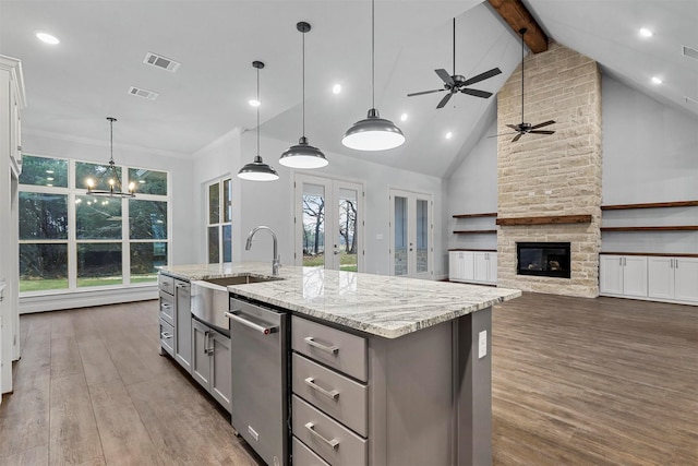 kitchen with decorative light fixtures, beamed ceiling, gray cabinetry, and an island with sink