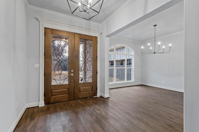 foyer entrance with dark hardwood / wood-style floors, a notable chandelier, ornamental molding, and french doors