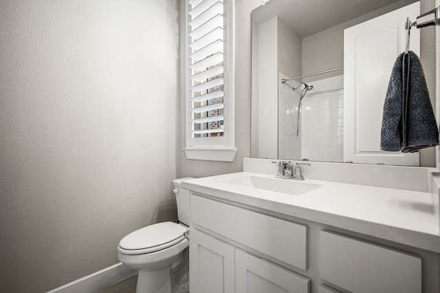 bathroom with toilet, vanity, and a tile shower