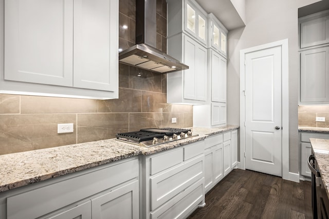 kitchen featuring light stone countertops, stainless steel gas cooktop, wall chimney range hood, white cabinets, and dark hardwood / wood-style floors