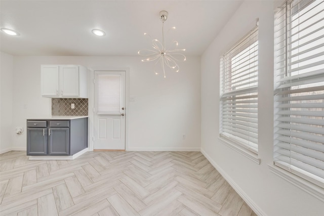 unfurnished dining area featuring light parquet floors and an inviting chandelier