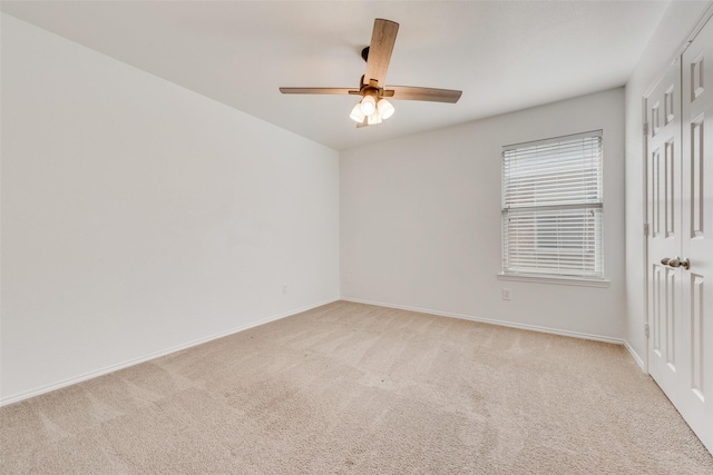 carpeted spare room featuring ceiling fan