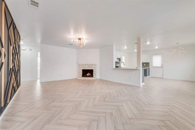 unfurnished living room featuring light parquet floors, sink, and an inviting chandelier