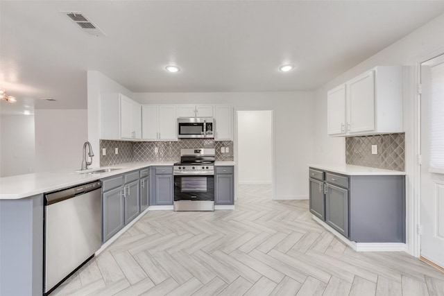 kitchen featuring appliances with stainless steel finishes, gray cabinetry, sink, kitchen peninsula, and light parquet flooring