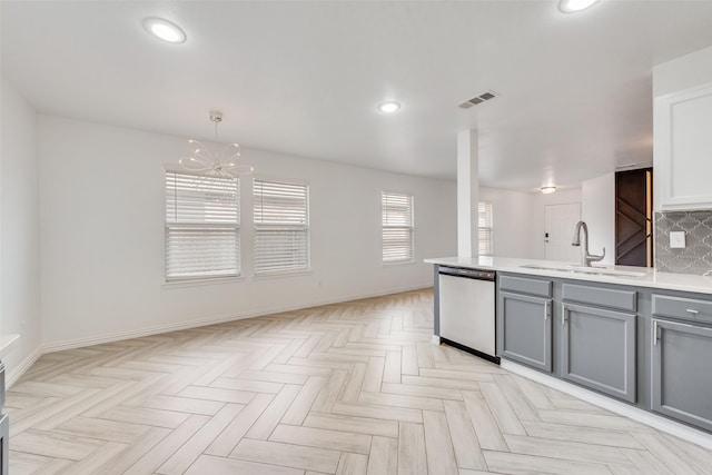 kitchen featuring stainless steel dishwasher, sink, pendant lighting, backsplash, and gray cabinets