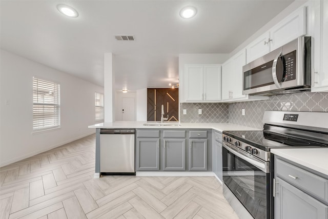 kitchen featuring kitchen peninsula, sink, white cabinetry, gray cabinets, and stainless steel appliances