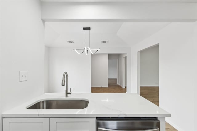 kitchen featuring dishwasher, sink, decorative light fixtures, white cabinetry, and light stone counters