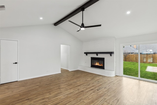 unfurnished living room featuring a fireplace, light hardwood / wood-style flooring, vaulted ceiling with beams, and ceiling fan