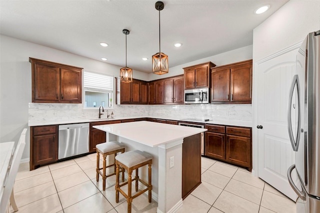 kitchen featuring a center island, appliances with stainless steel finishes, light tile patterned floors, sink, and decorative light fixtures