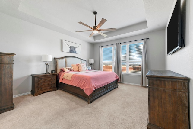 bedroom featuring ceiling fan, light colored carpet, and a raised ceiling