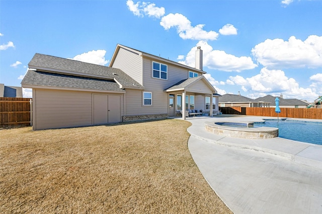 back of property featuring a swimming pool with hot tub, a lawn, and a patio area