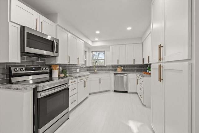 kitchen featuring decorative backsplash, sink, white cabinetry, and stainless steel appliances