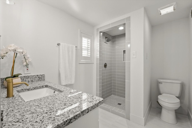 bathroom with a tile shower, toilet, tile patterned floors, and vanity