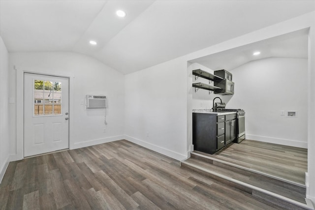 interior space with dark wood-type flooring, a wall unit AC, and lofted ceiling