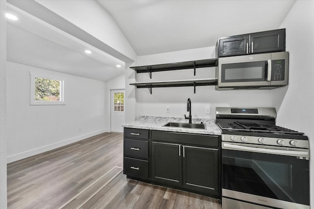 kitchen with light stone countertops, appliances with stainless steel finishes, sink, dark hardwood / wood-style floors, and vaulted ceiling