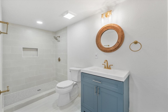 bathroom featuring toilet, vanity, and tiled shower