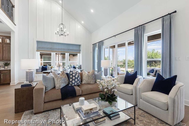 living room with high vaulted ceiling, light hardwood / wood-style flooring, and a chandelier