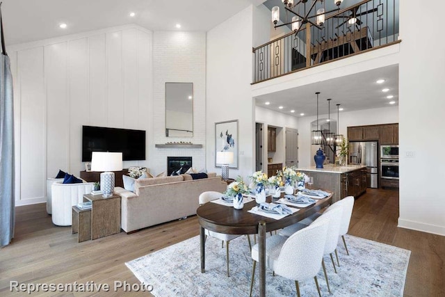 dining space featuring a chandelier, a high ceiling, a fireplace, and wood-type flooring