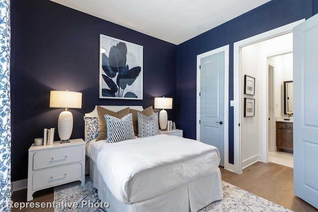 bedroom featuring ensuite bathroom and light hardwood / wood-style flooring