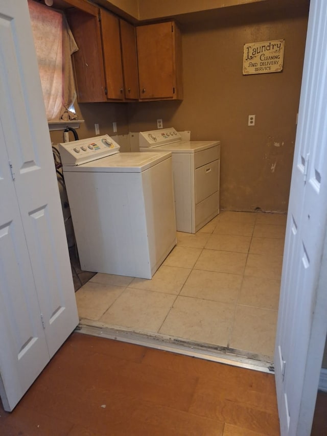 laundry area featuring light tile patterned floors, washing machine and dryer, and cabinet space