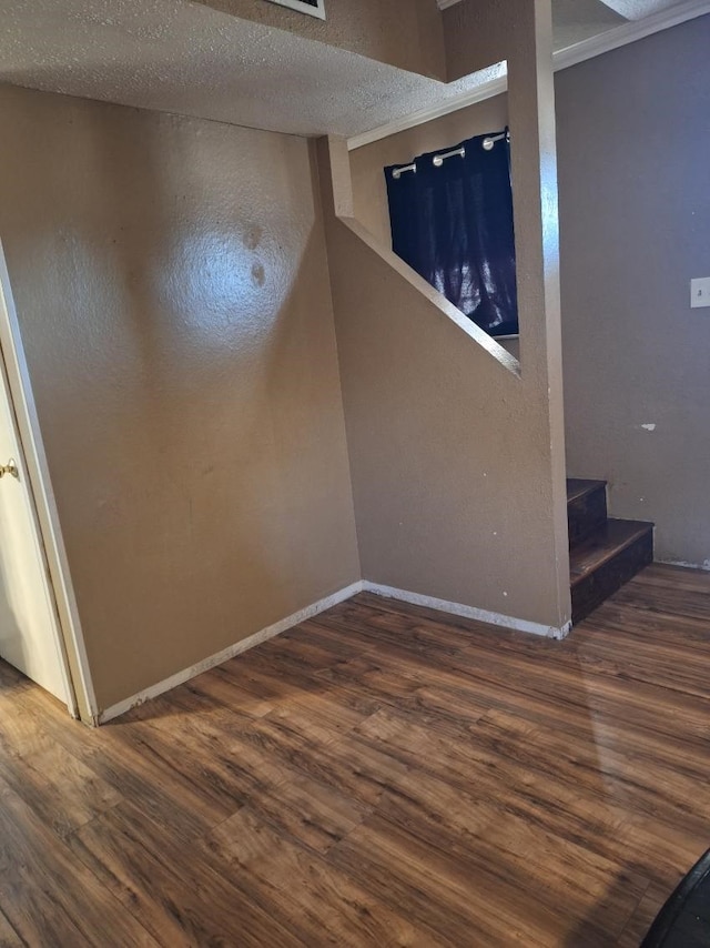 below grade area featuring dark wood-style floors, baseboards, stairway, and a textured ceiling