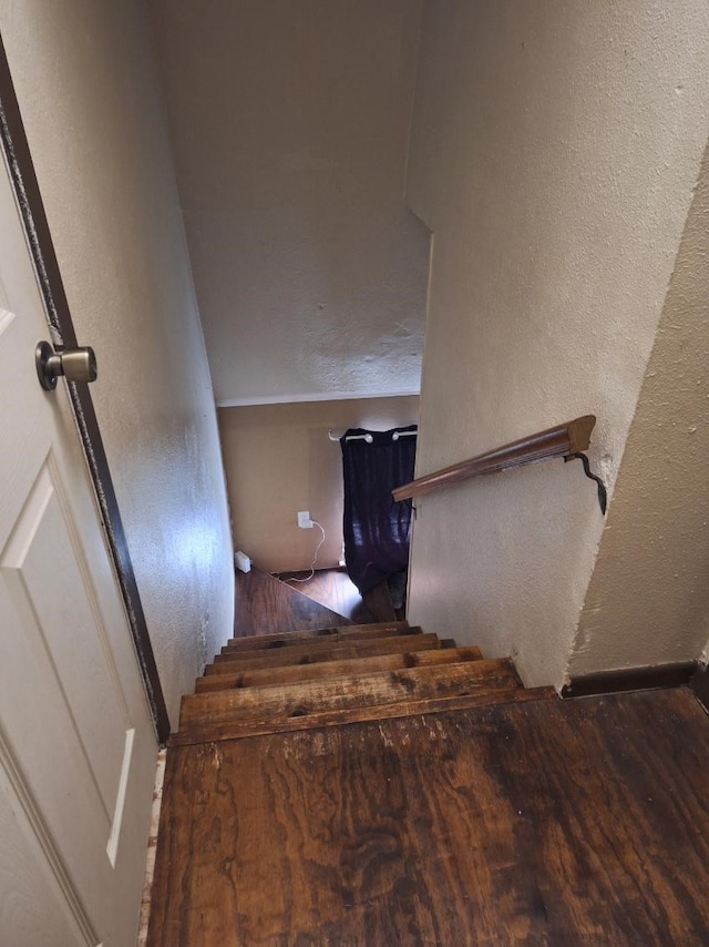 stairs with a textured wall and wood finished floors