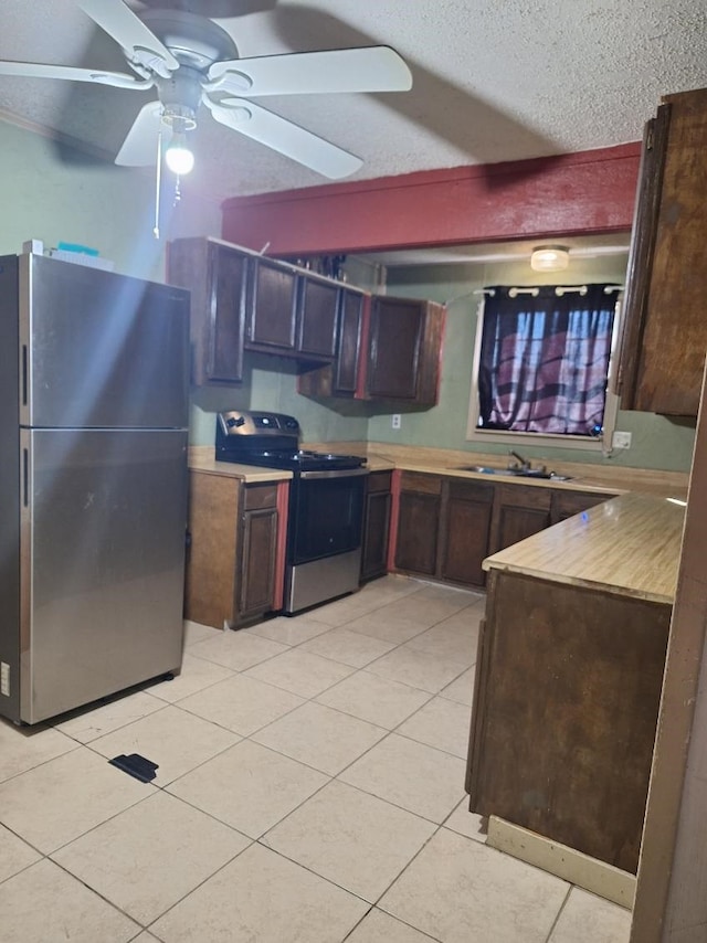 kitchen featuring light tile patterned floors, stainless steel appliances, light countertops, a sink, and a textured ceiling