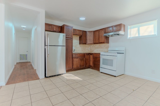 kitchen featuring light tile patterned floors, stainless steel fridge, white range, and tasteful backsplash