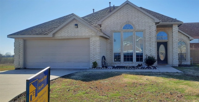 french country home featuring a front lawn, concrete driveway, brick siding, and an attached garage