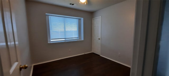 unfurnished room with dark wood-style floors, visible vents, and baseboards