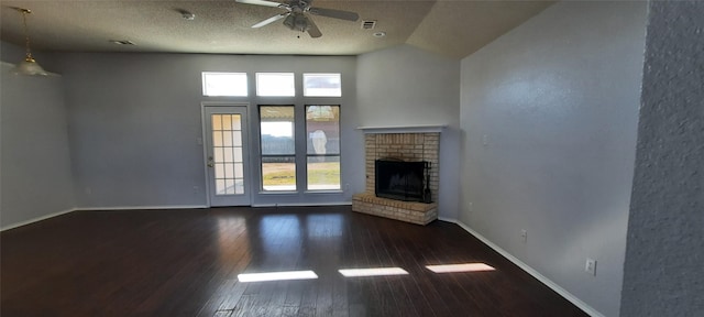 unfurnished living room with ceiling fan, dark wood-type flooring, a wealth of natural light, and a brick fireplace