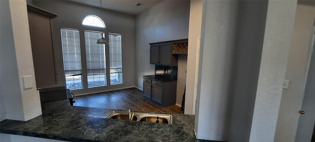 kitchen with dark wood-style flooring, visible vents, a sink, and decorative light fixtures