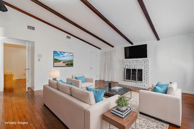 unfurnished living room featuring a brick fireplace, wood-type flooring, and lofted ceiling with beams